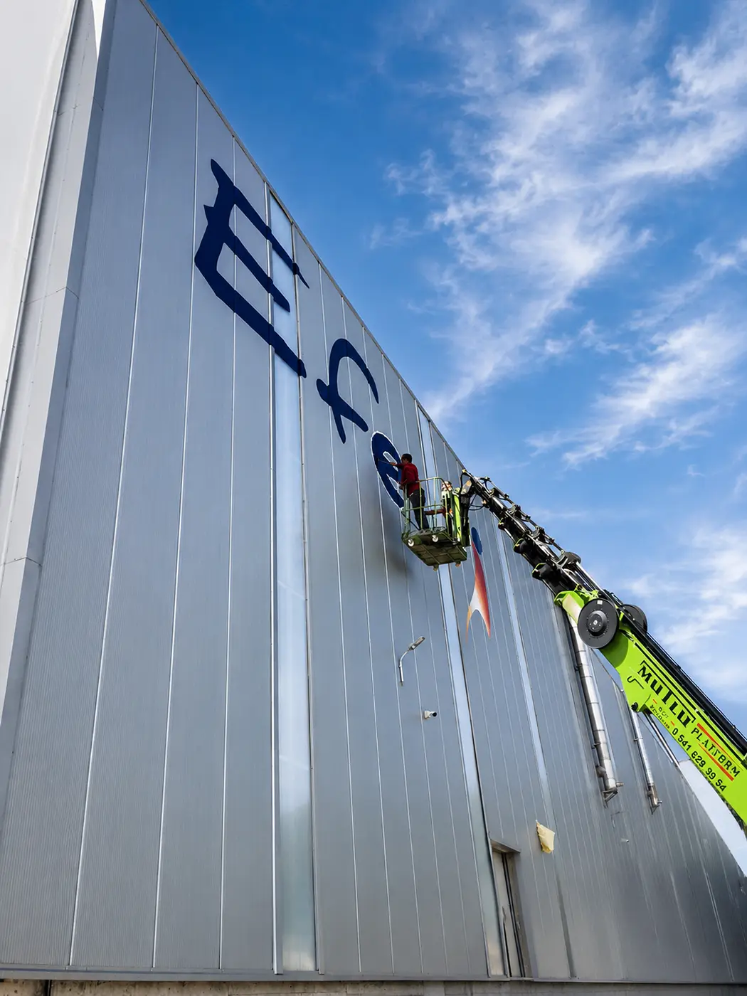 Worker on an elevated platform during Efectis façade logo work