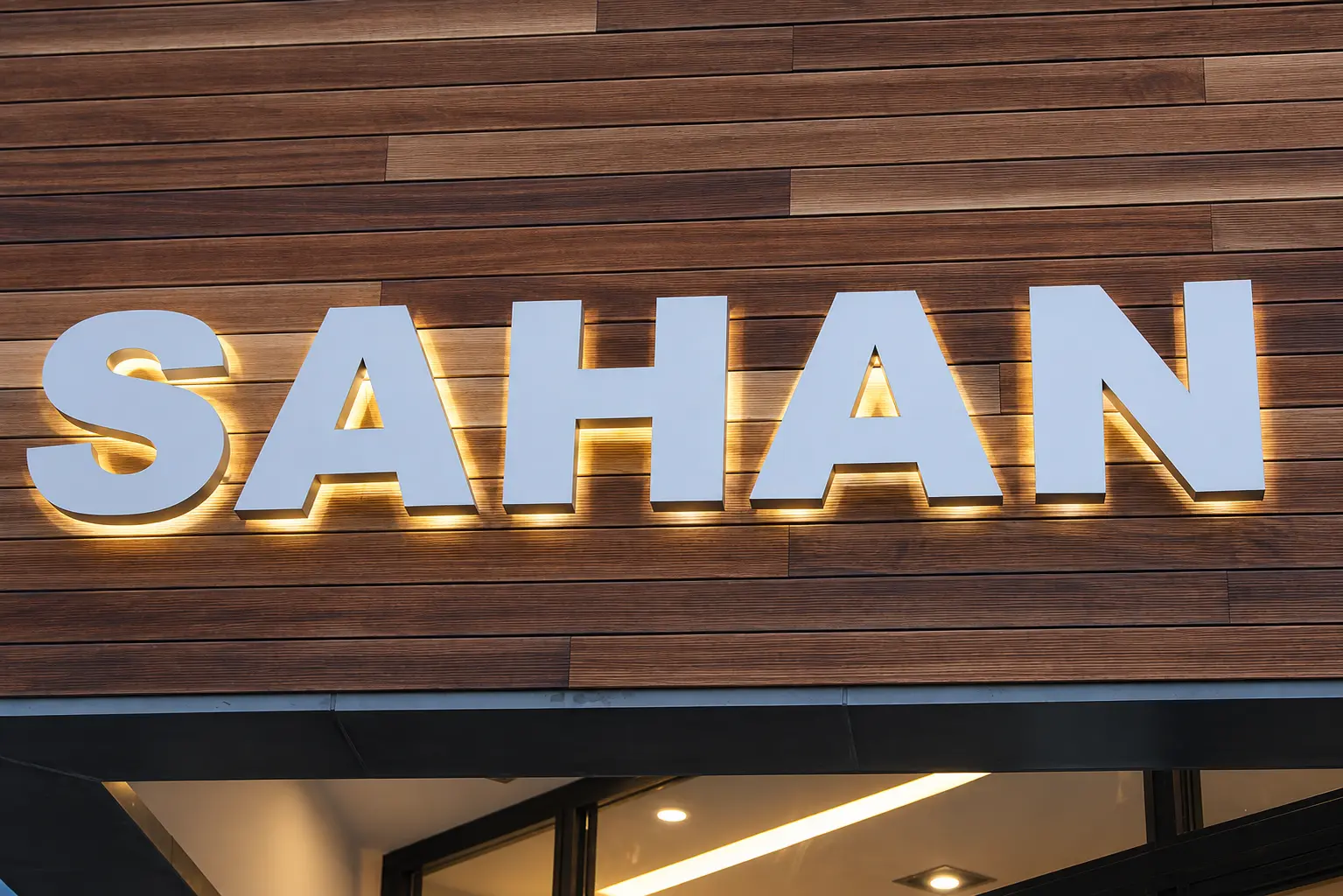 Halo-lit stainless steel SAHAN letters on the wood-clad façade