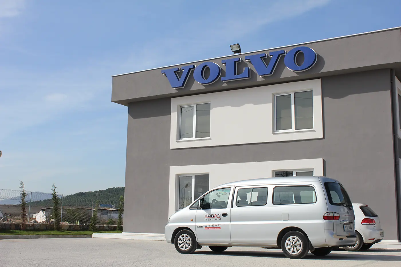 Close exterior view of blue dimensional VOLVO letters mounted on a gray facade