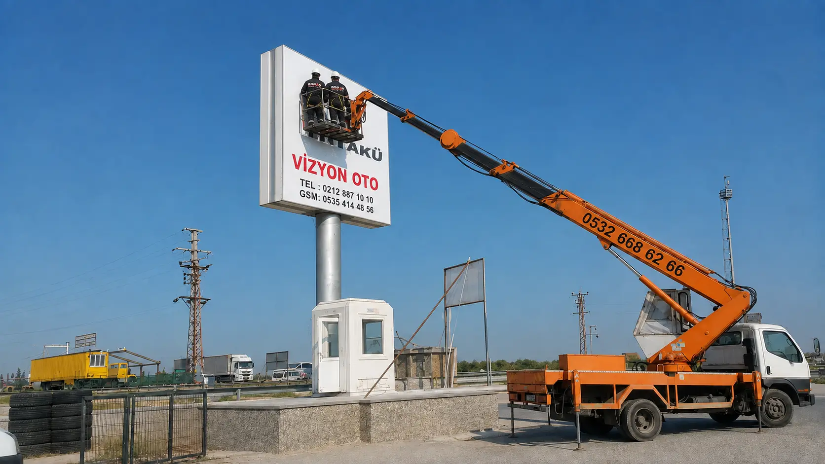 Wide view of Boran Reklam installers working on the Yiğit Akü roadside pylon sign