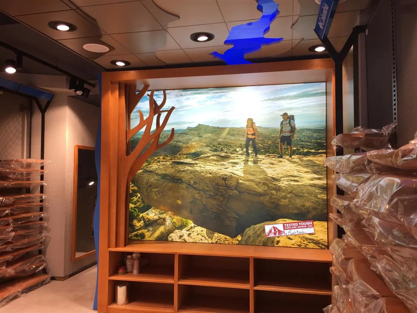 Framed Columbia Tested Tough backlit display featuring hikers in a rocky outdoor landscape