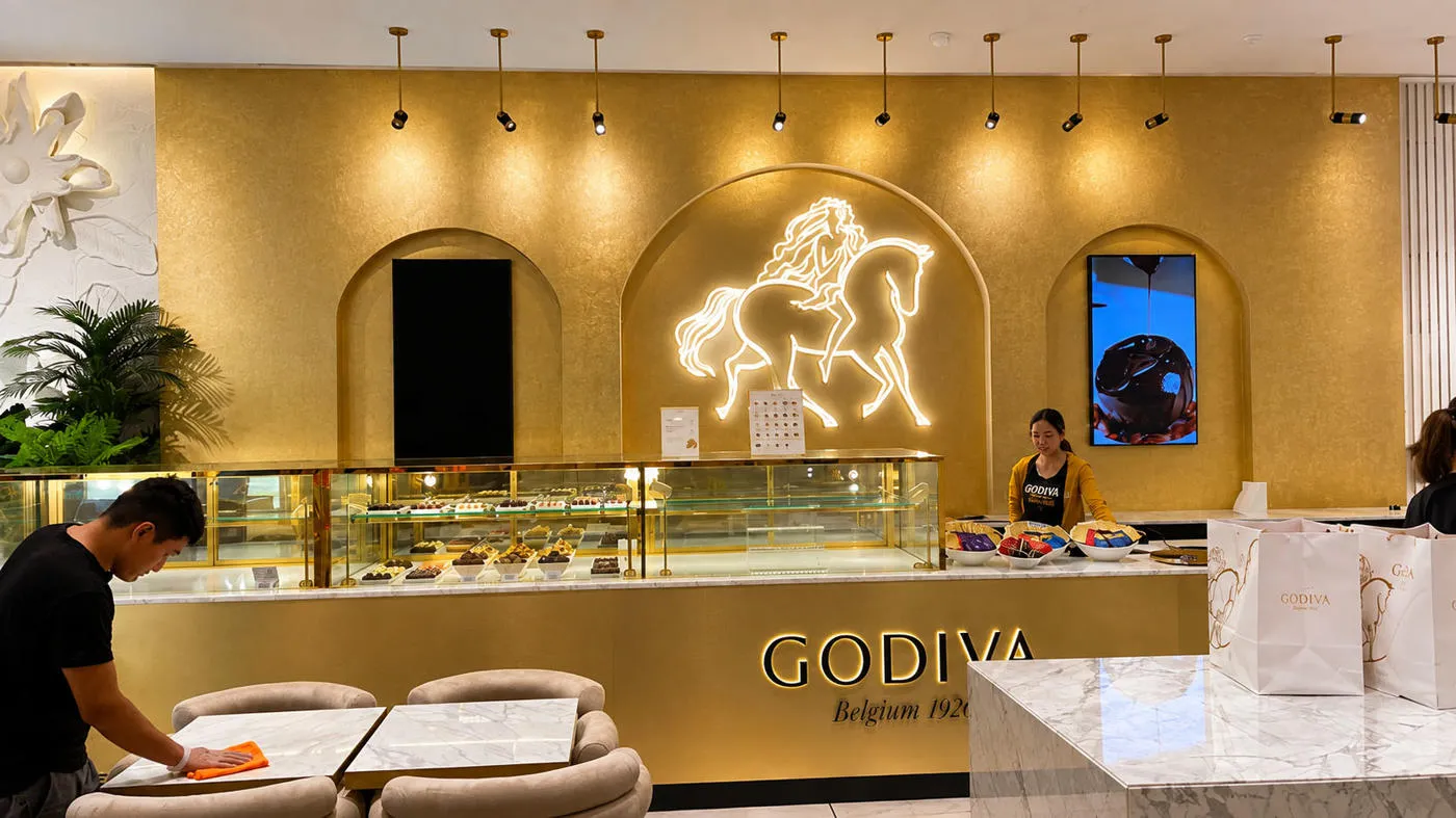Godiva Café interior with an illuminated horse emblem and backlit counter signage
