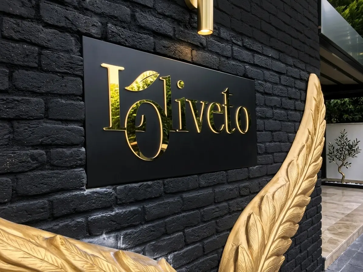Gold Loliveto logo on a black panel mounted to a dark brick wall