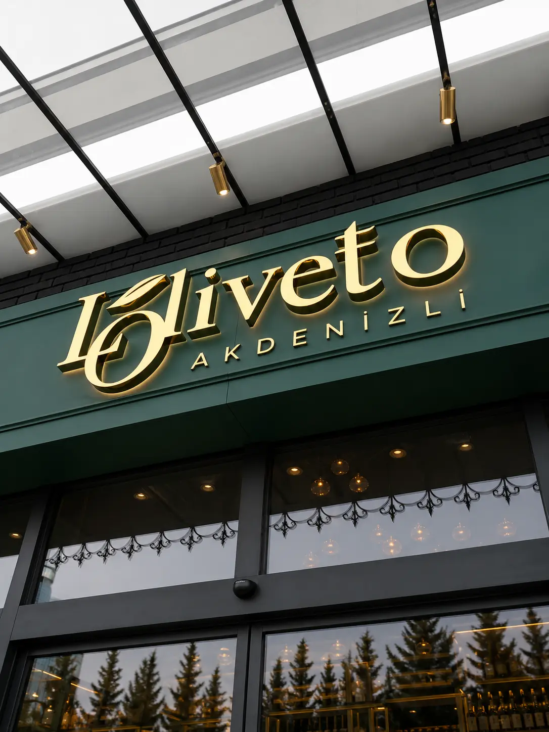 Close view of gold Loliveto letters with warm halo lighting above the entrance