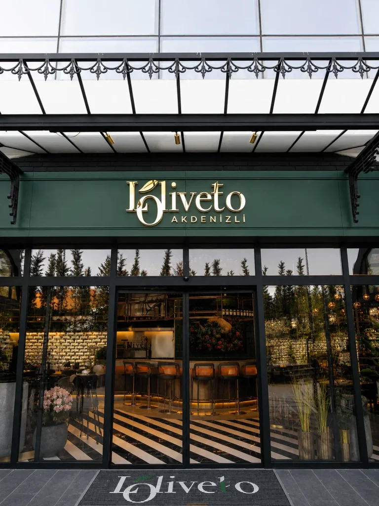 Loliveto restaurant entrance with gold halo-lit letters on a green facade