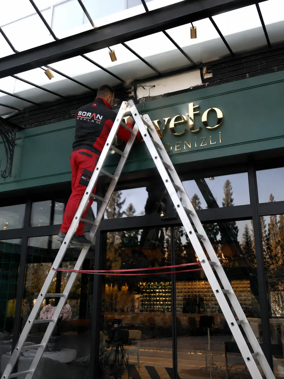 Boran Reklam team member installing the gold Loliveto entrance letters