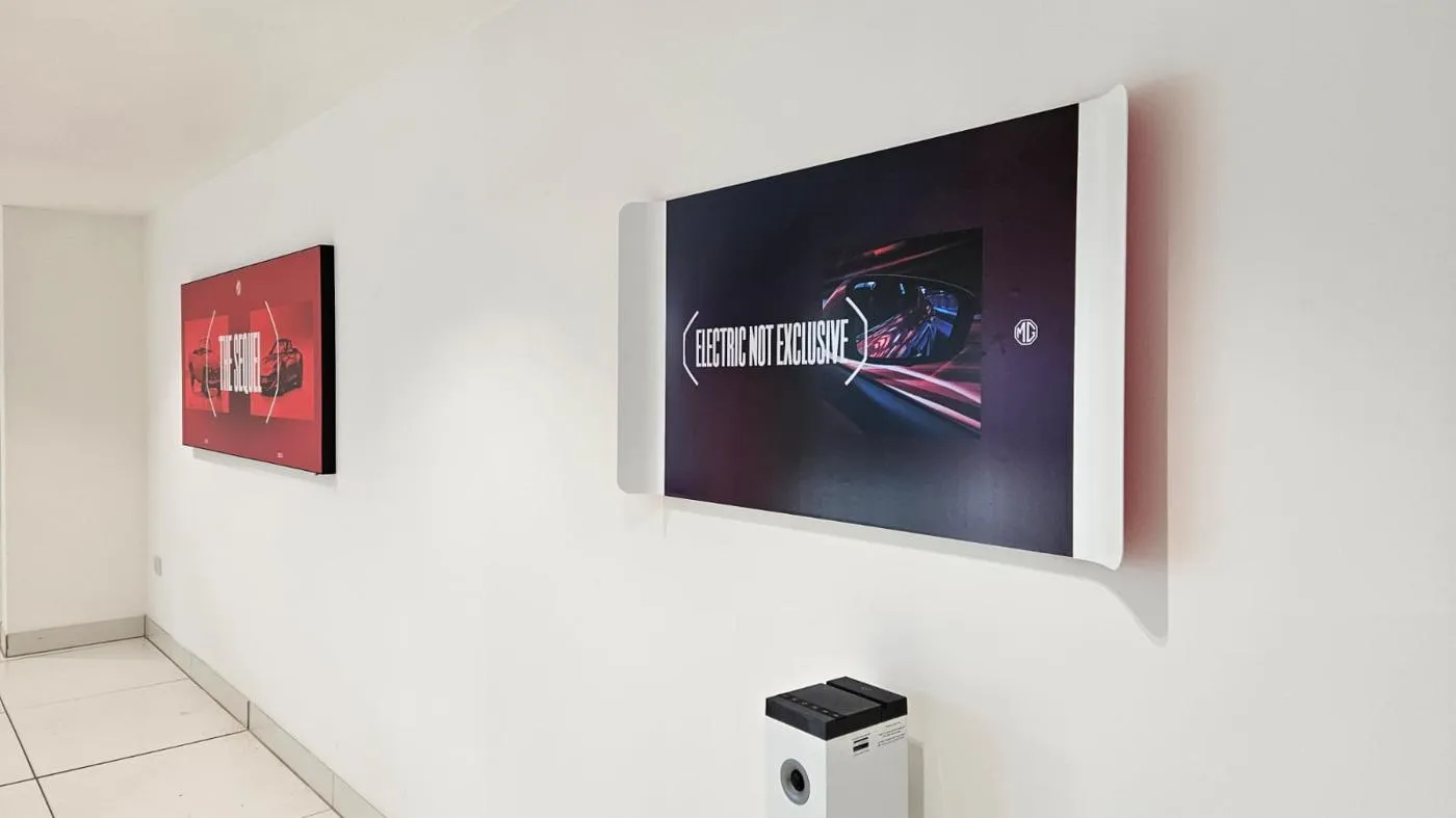 Wall-mounted MG campaign lightboxes installed inside a UK dealership