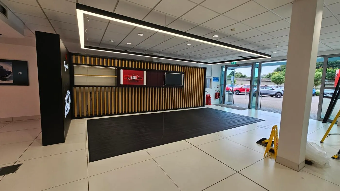 MG showroom vehicle display zone with illuminated ceiling frame and campaign graphics