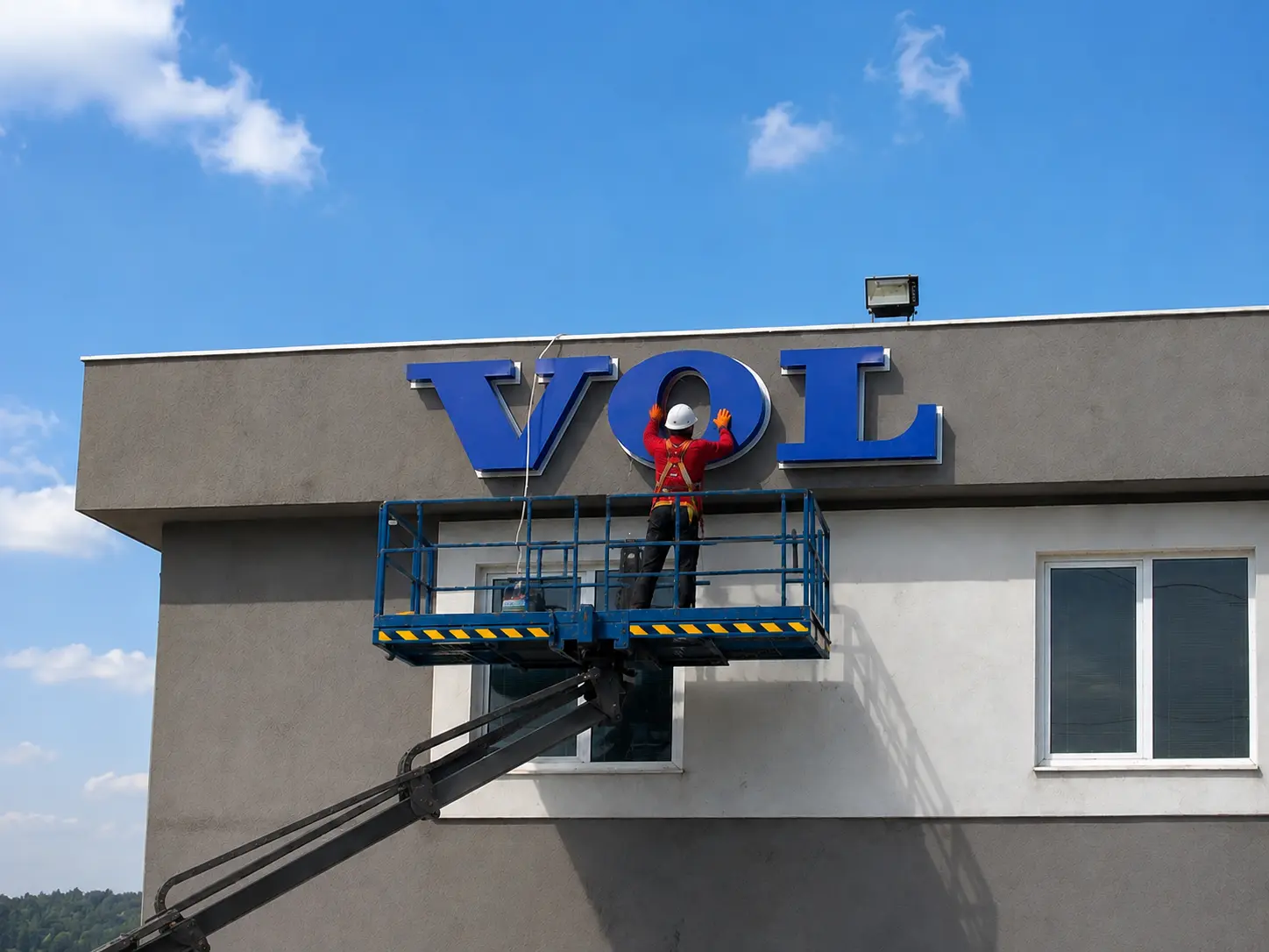 Boran Reklam team member installing blue VOLVO letters from an aerial lift