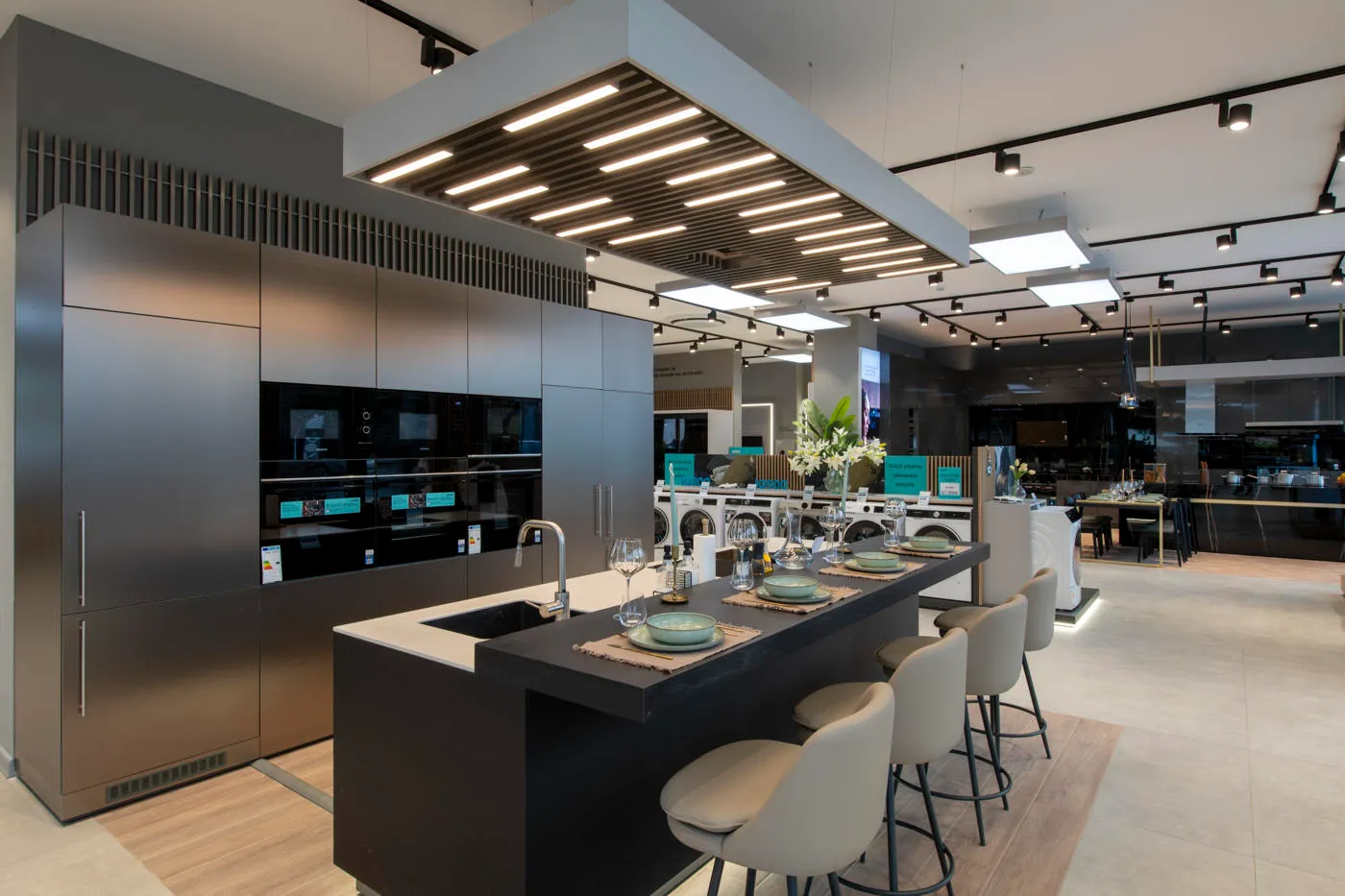 Wide Siemens experience kitchen showroom with built-in appliances, dining island and coordinated retail displays