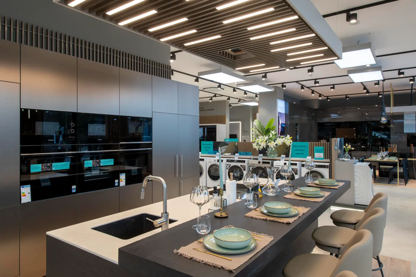 Siemens built-in kitchen appliance display with ovens, island setting and illuminated ceiling feature