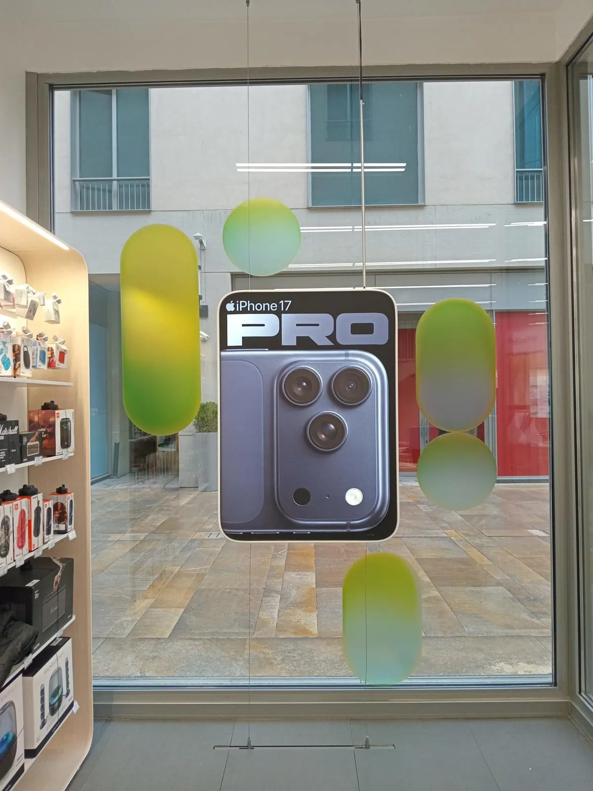Suspended iPhone 17 Pro promotional display and green window graphics inside a TROY Apple Premium Partner store